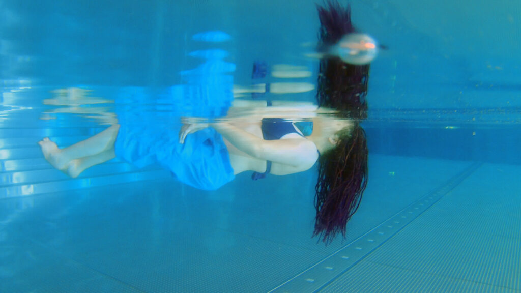 Eine Unterwasser-Aufnahme von Eva-Maria beim Schwimmen in einem blauen Badeanzug.